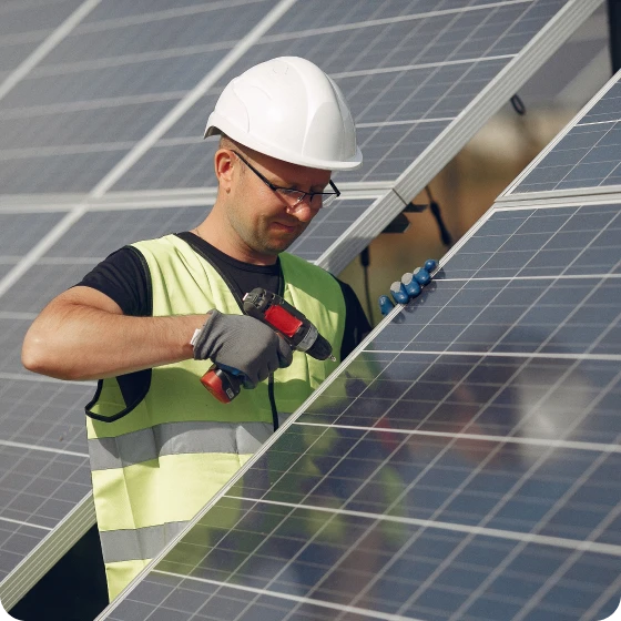 A man in a hard hat and safety vest diligently working on solar panels.